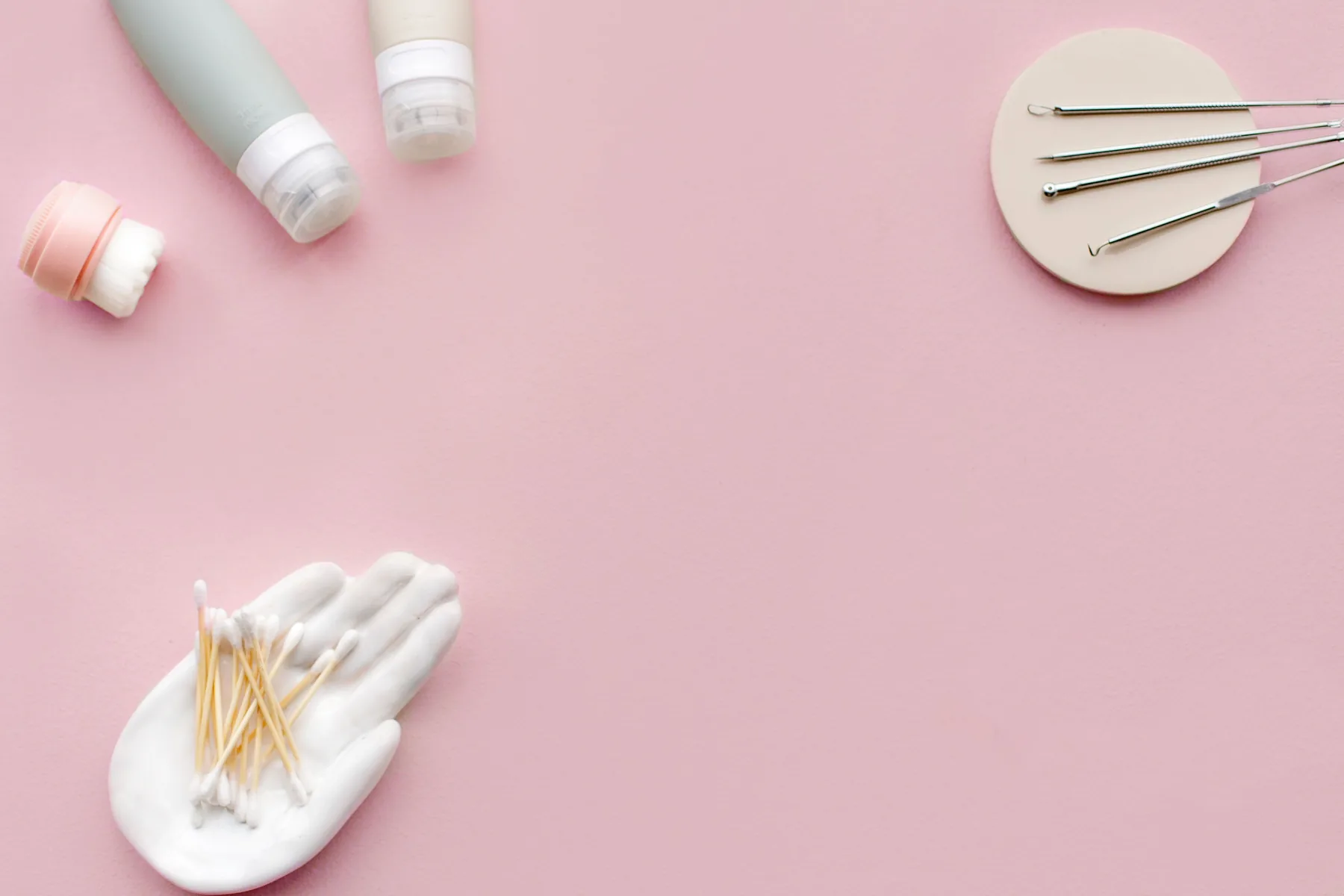 Premium skincare accessories arranged on a soft pink surface